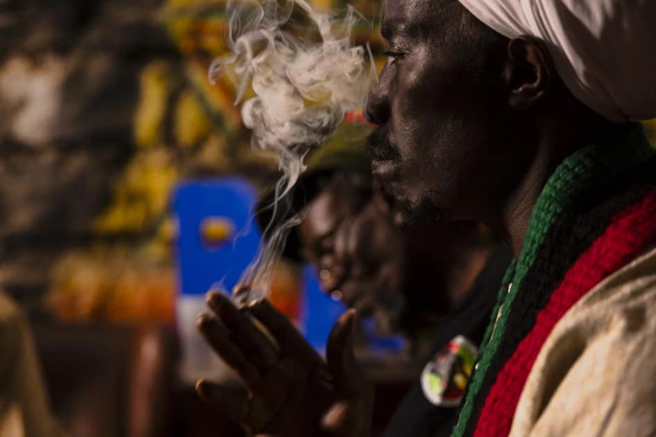 Rastafarian men holding hands in prayer beneath a portrait of Emperor Haile Selassie I in Nairobi, Kenya.